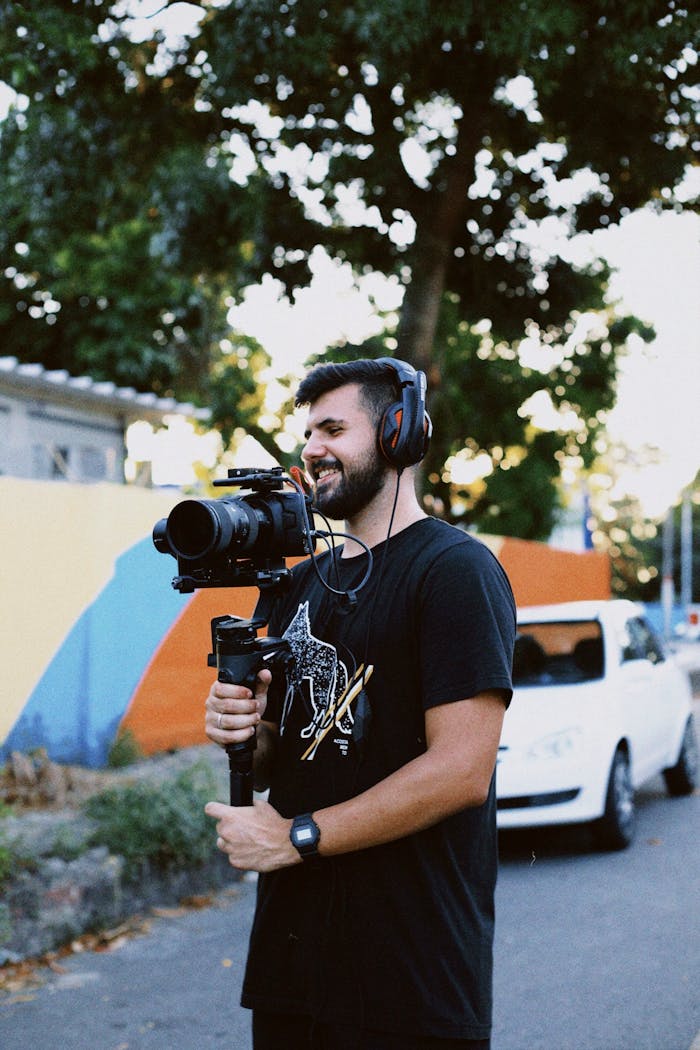 Photographer with camera and headphones filming outdoors in sunny Maricá, Brazil.